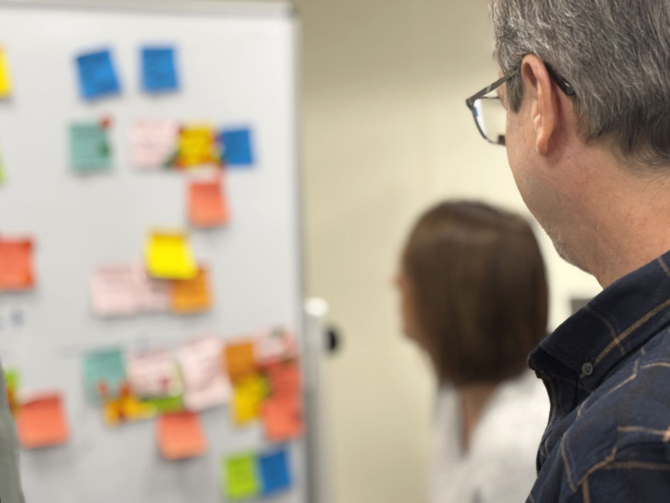 A photo of a group doing a SWOT matrix together, with one person in the foreground looking on