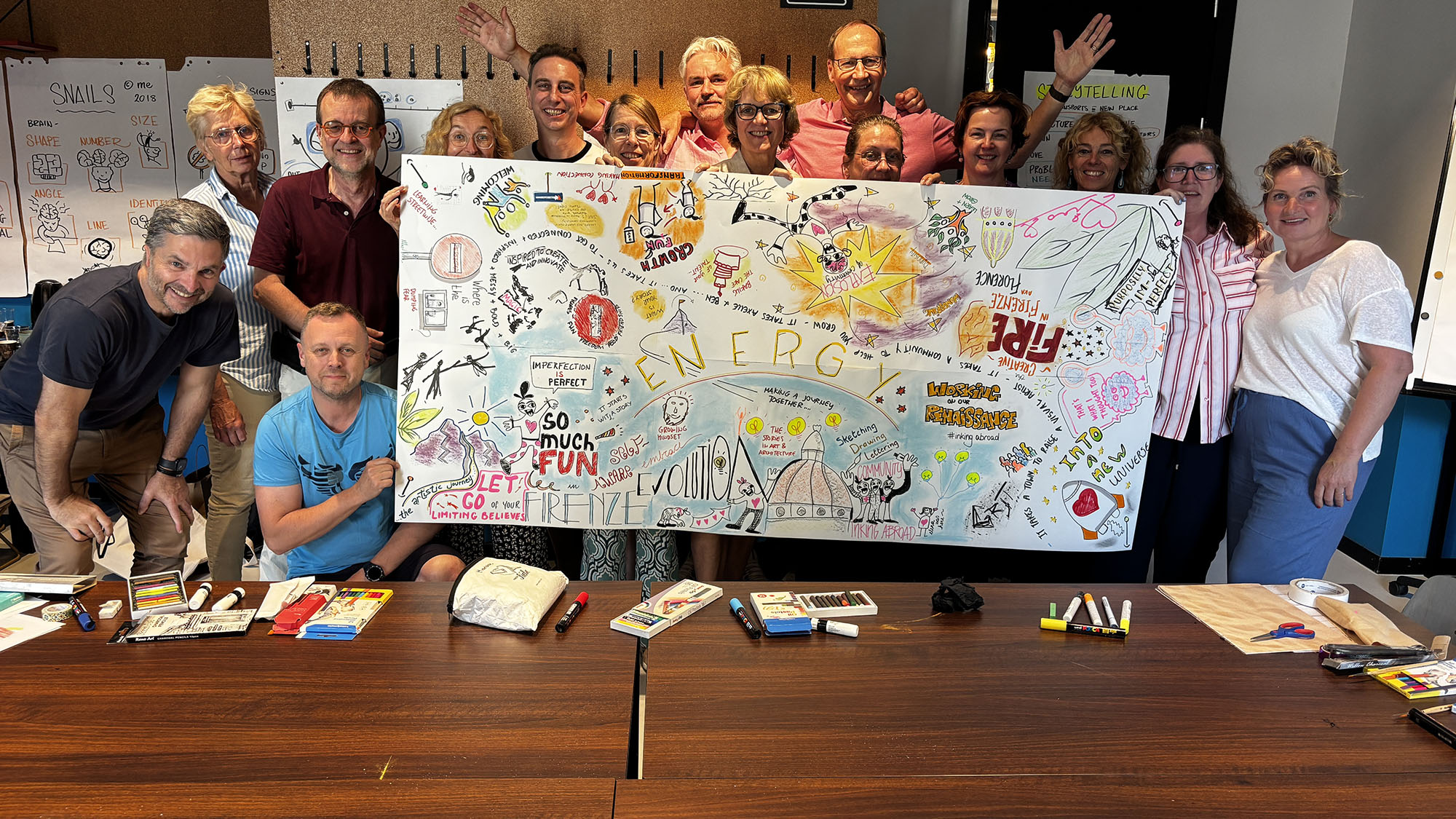 A photo of all of our workshop attendees holding up a group drawing they did together