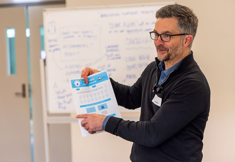 A photo of Ben Crothers facilitating a workshop using a prototype of a patient brochure