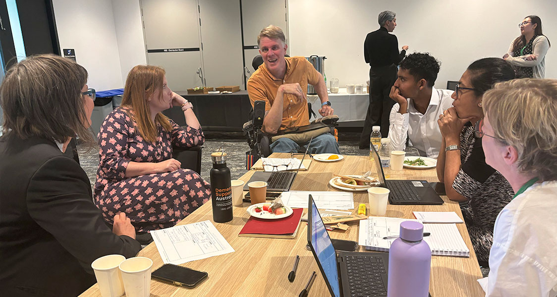 Photo of a group having a conversation in a CDRP workshop, with someone with a disability in a wheelchair leading the discussion